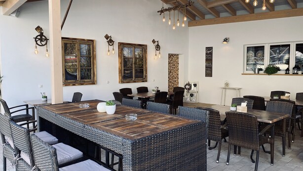 Un restaurante con una larga mesa de madera, sillas de mimbre y lámparas colgantes.