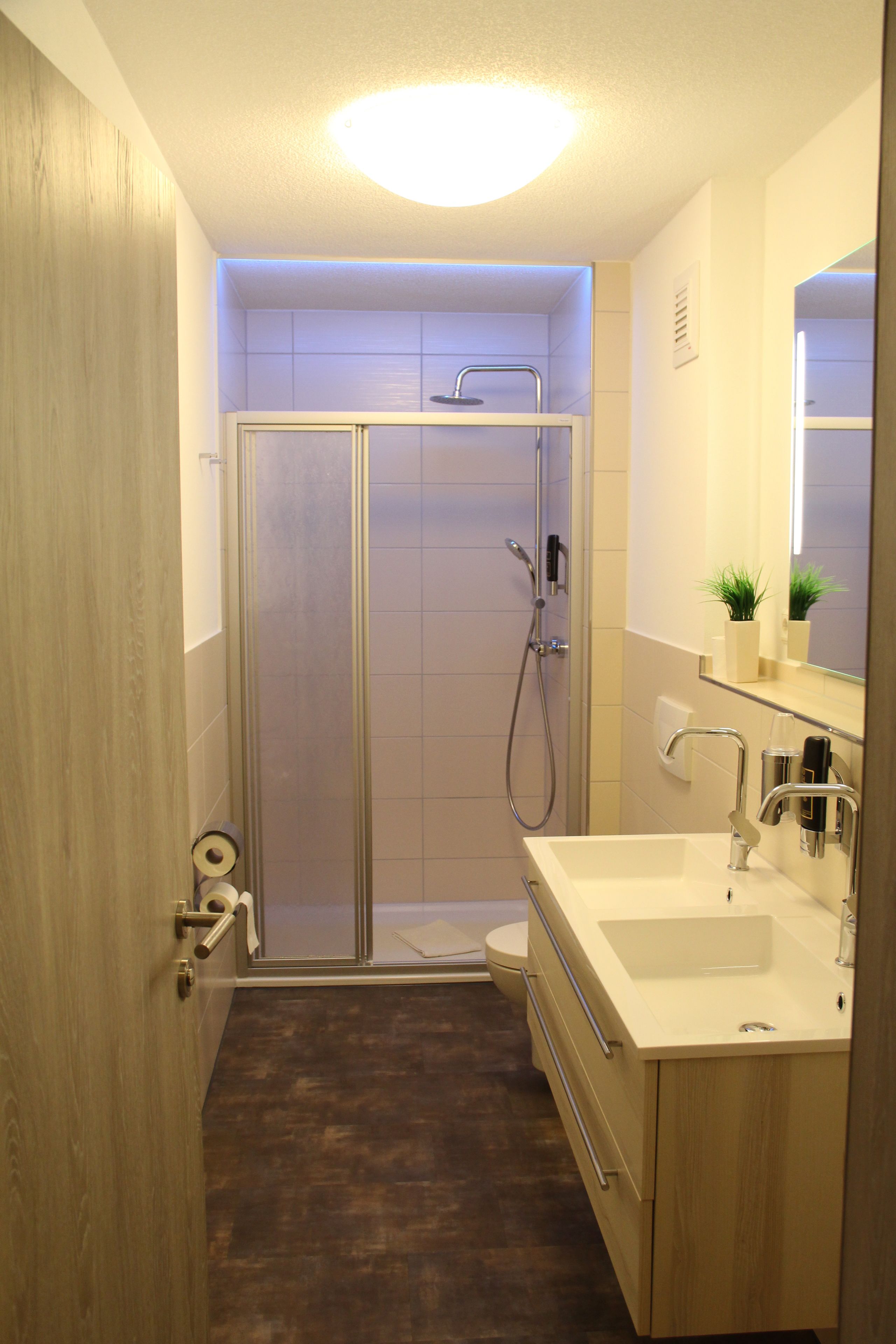 A modern bathroom with a glass-enclosed shower, a sink with a mirror, and wooden cabinetry.