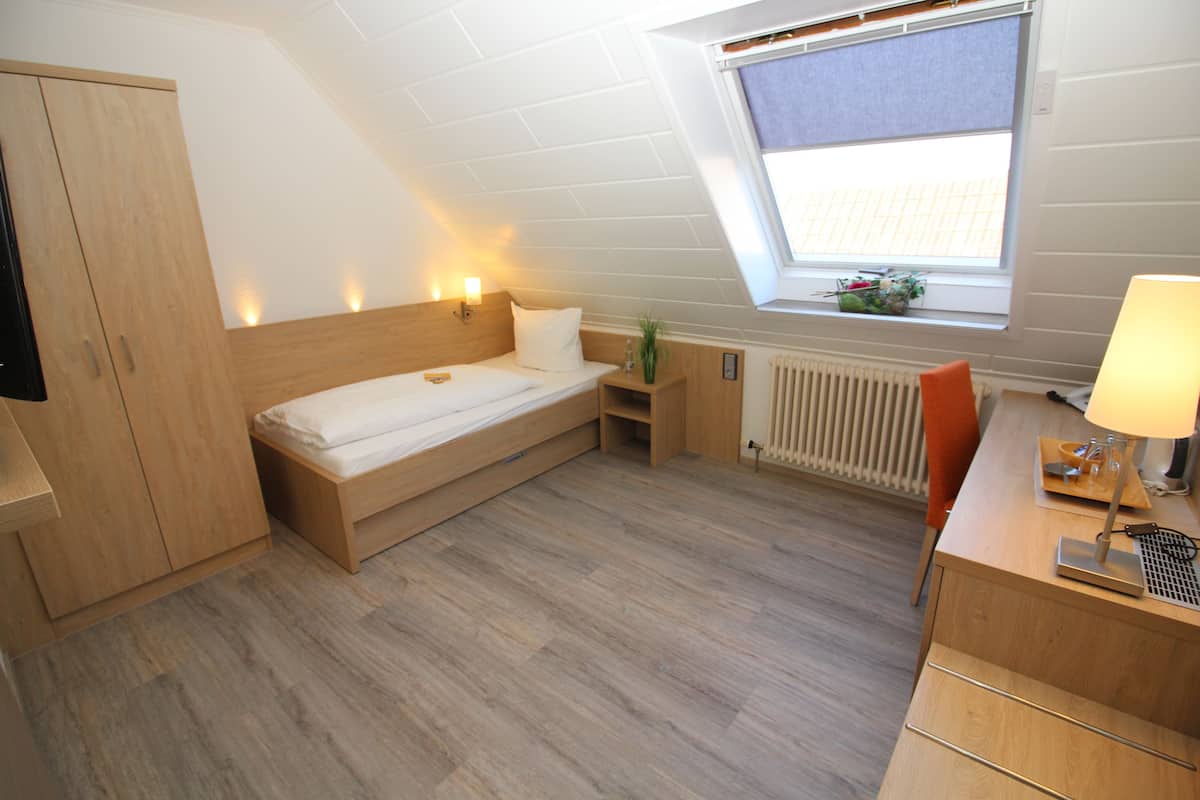 Una habitación pequeña y moderna con cama entrepiso, un escritorio con lámpara, un radiador y una ventana con vistas.