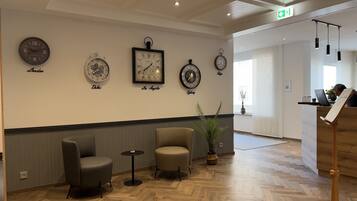 Eine Lobby mit Holzdielenmuster-Boden, einem Empfangstresen und Uhren mit Stadtbezeichnungen.