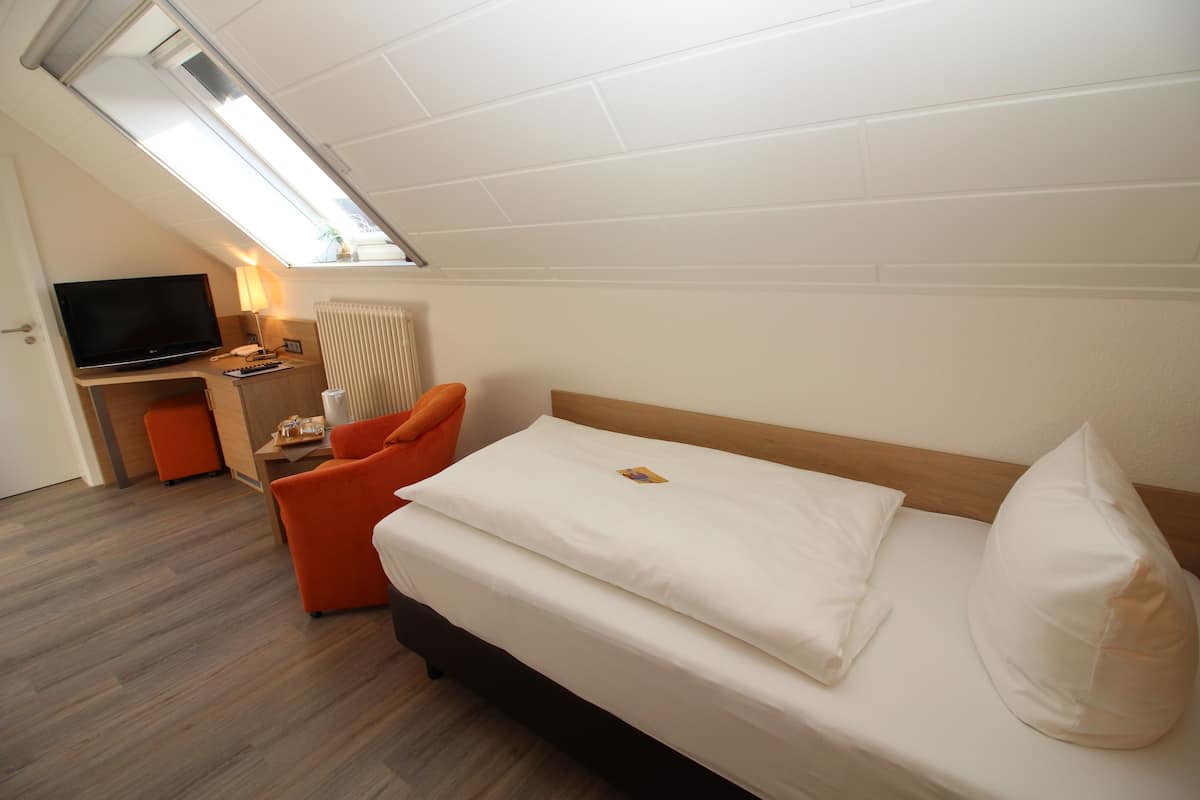 Una habitación moderna con una cama, un escritorio, un televisor y una ventana.