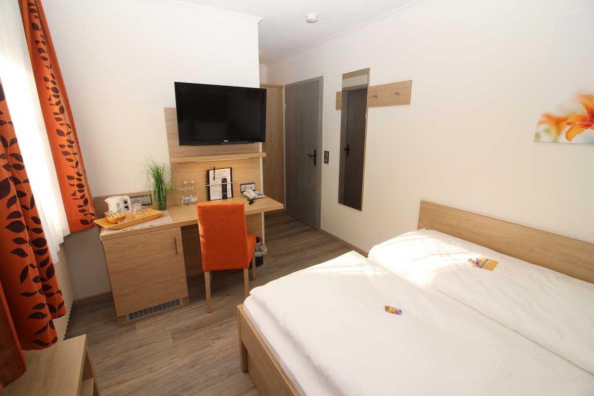 Una habitación de hotel con una cama, un escritorio con una silla, un televisor y una puerta.