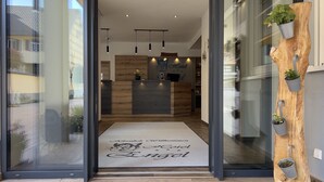 Zona de recepción de un hotel con un mostrador de madera, un cartel de recepción y un felpudo de bienvenida.