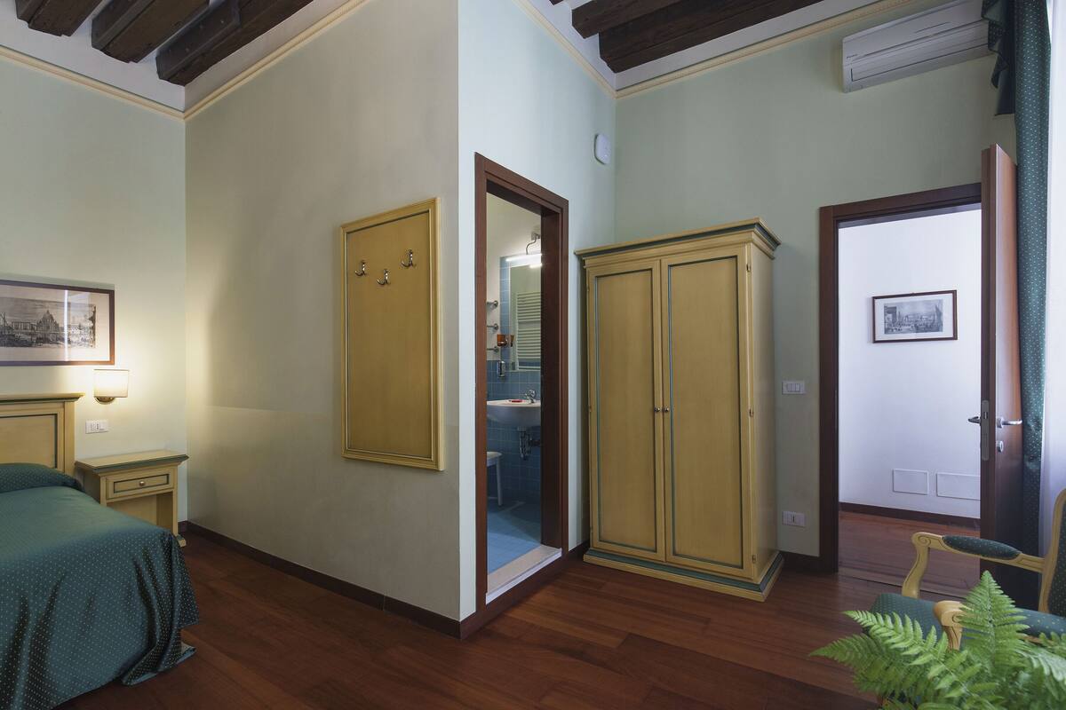 A room with a bed, a wardrobe, a chair, and a small table.