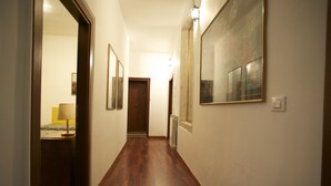 A hallway with wooden flooring, a bed with a lamp, and a door at the end. - Zaguri Bed and Breakfast (Venice)