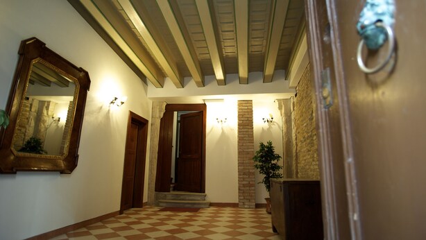 A hallway with a checkered floor, a wooden door, a mirror, and a wall-mounted light fixture. - Zaguri Bed and Breakfast (Venice)