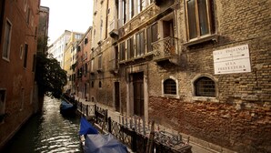 A narrow canal with buildings on either side, a gondola docked on the left, and a sign reading "ALIA PROVINCIA PREFETTURA" on the right. - Zaguri Bed and Breakfast (Venice)