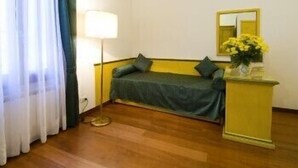 A room with a bed, a bedside table with a lamp, a mirror, and a vase with flowers. - Zaguri Bed and Breakfast (Venice)