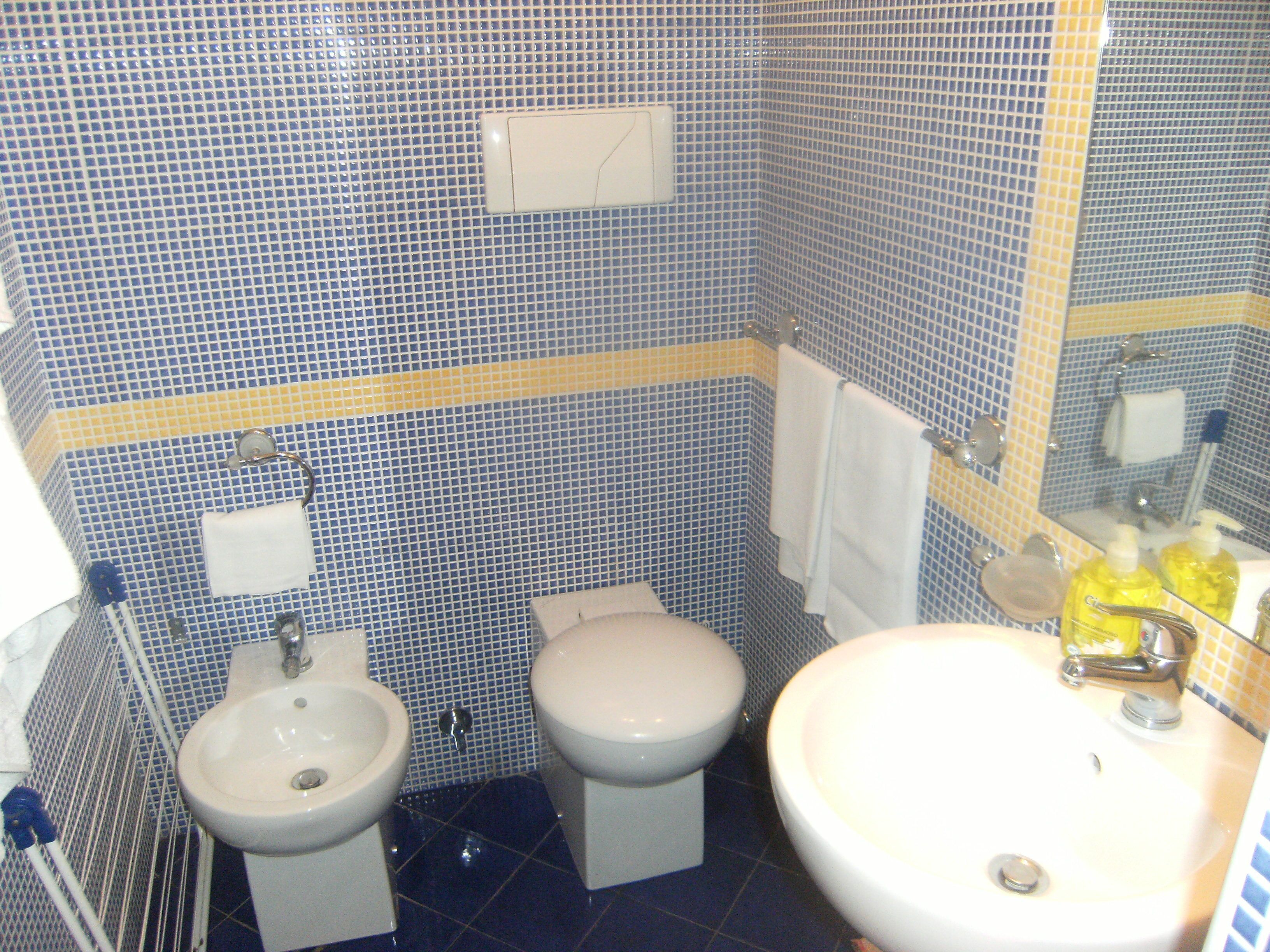 A bathroom with a sink, two toilets, and a mirror.