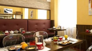 A breakfast setting with a table set for two, including plates, bowls, cups, and a variety of breakfast items. - Panizza (Milan)
