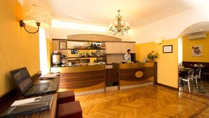 A hotel lobby with a bar area, wooden flooring, and a receptionist at the counter. - Panizza (Milan)