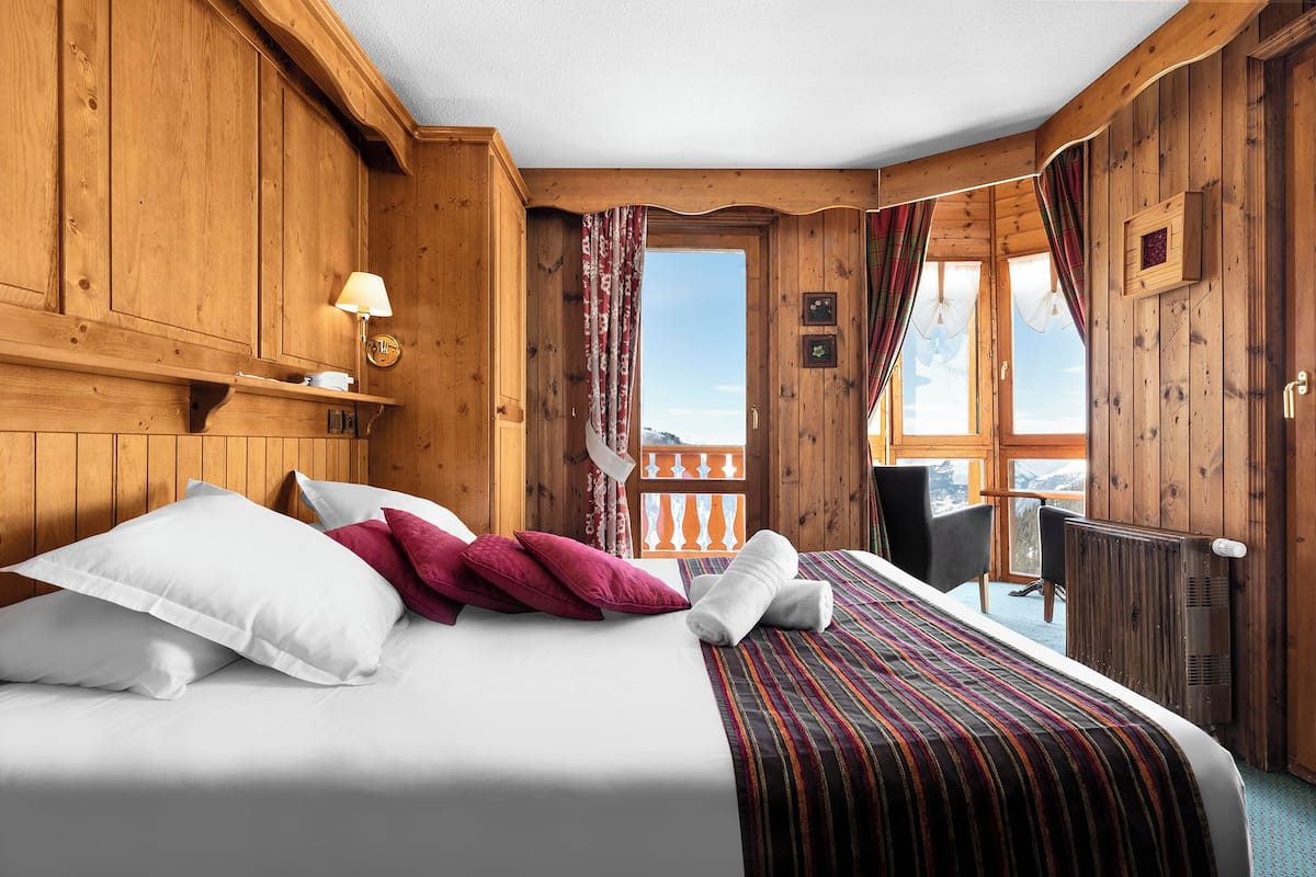 A wooden room with a bed, a window, and a view of the outdoors.