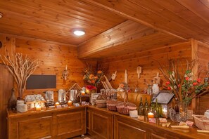 A wooden cabin interior with a bar area, wooden walls, and various amenities like candles, baskets, and a fireplace. - Hotel Les Balcons Village & Spa Belle Plagne (La Plagne-Tarentaise)