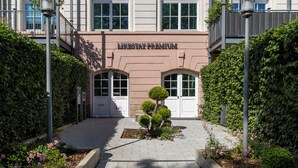 Un edificio con un letrero que dice 'LIKESTAY PREMIUM', un árbol pequeño y un sendero pavimentado.