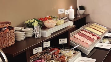 A buffet with various food options including salads, meats, and a candle for ambiance.