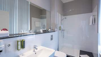 Une salle de bain moderne avec un lavabo blanc, des toilettes et une douche à parois de verre.