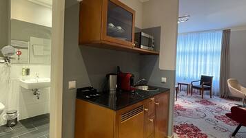 A compact kitchen with a microwave, coffee maker, and a cabinet with a glass door.