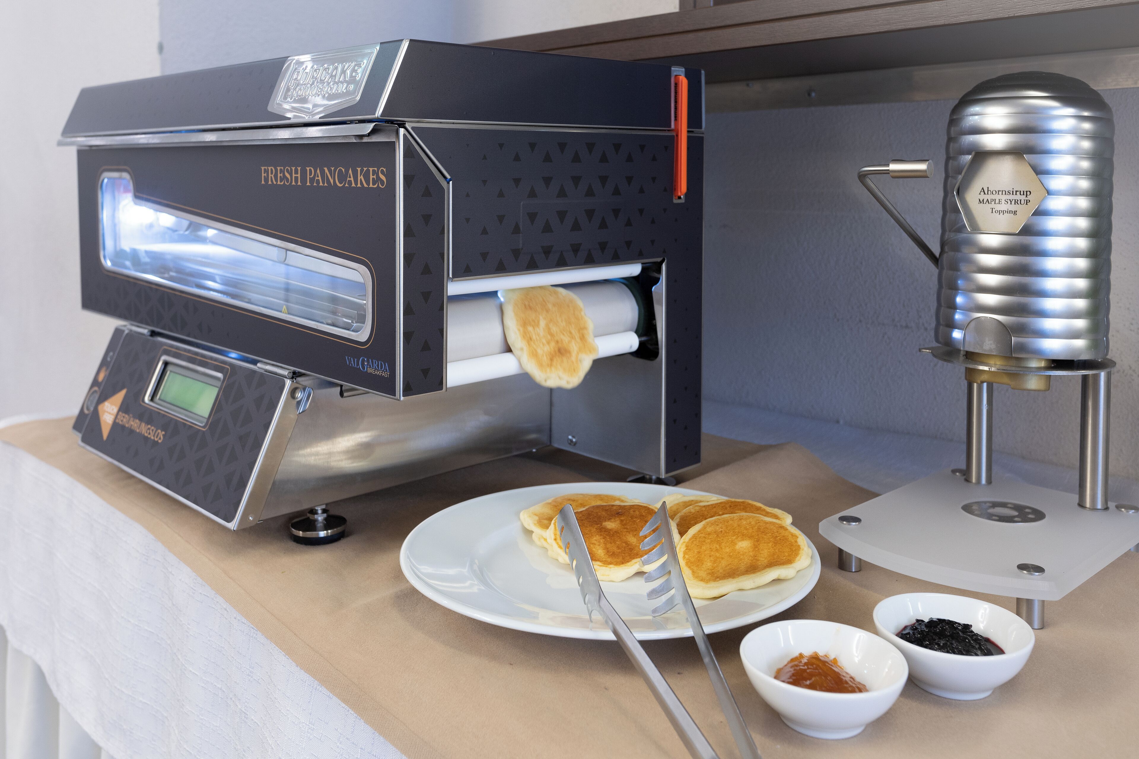 A commercial kitchen with a fresh pancake maker and syrup dispenser.