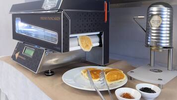 A commercial kitchen with a fresh pancake maker and syrup dispenser.
