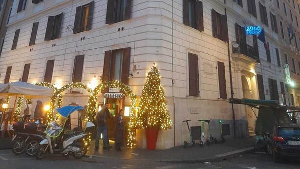 Un hotel de varios pisos con un estilo arquitectónico clásico, que presenta una entrada en esquina y una señal visible para recorridos por el hotel.