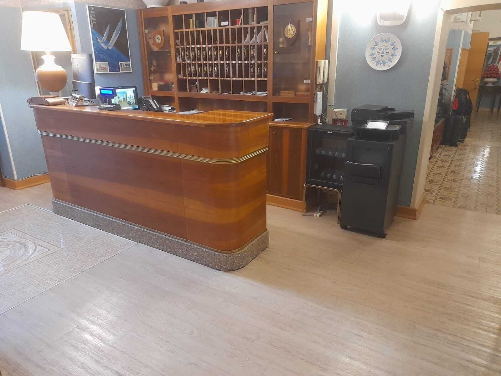A reception desk with a wooden finish, a computer, and a telephone.