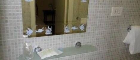 A bathroom with a white sink, a mirror, and a tiled wall.