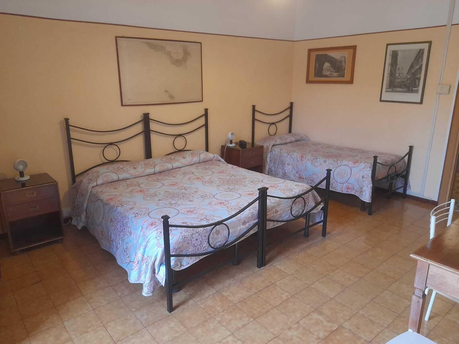 A bedroom with two beds, a nightstand, and a chair.