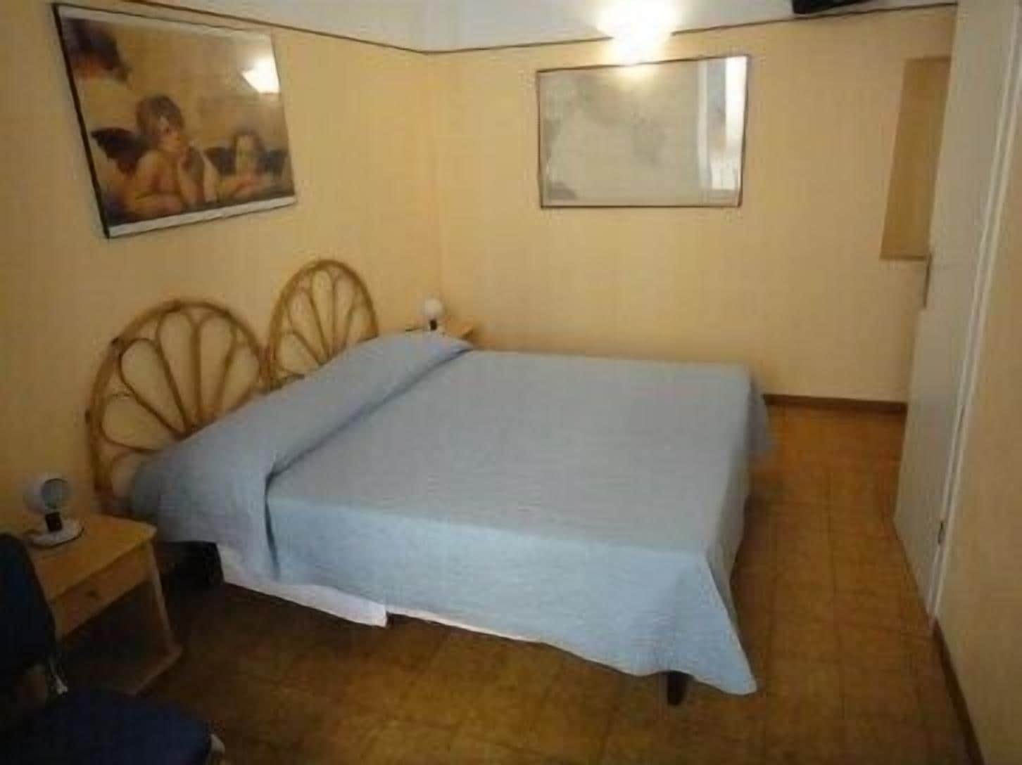 Un dormitorio pequeño y ordenado con una cama individual, una mesita de noche y una silla.