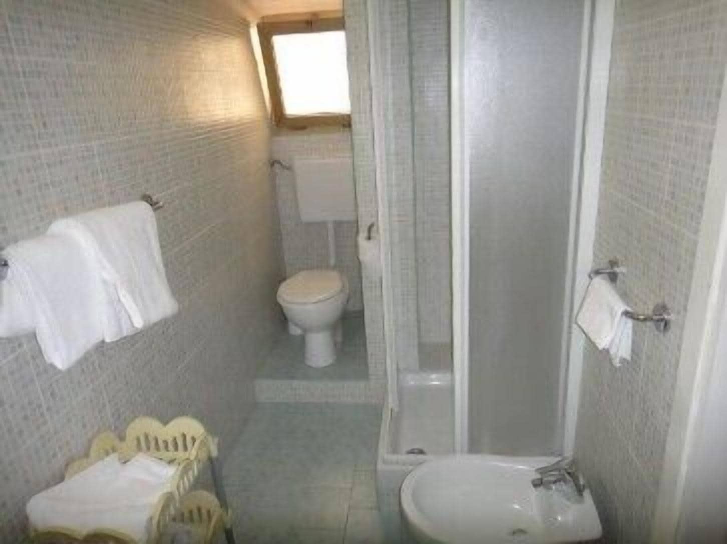 Uma casa de banho pequena com sanita, lavatório e chuveiro.