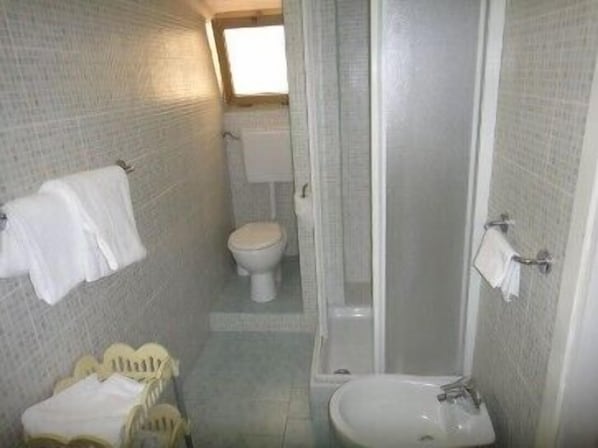 Un baño pequeño con inodoro, lavamanos y ducha.