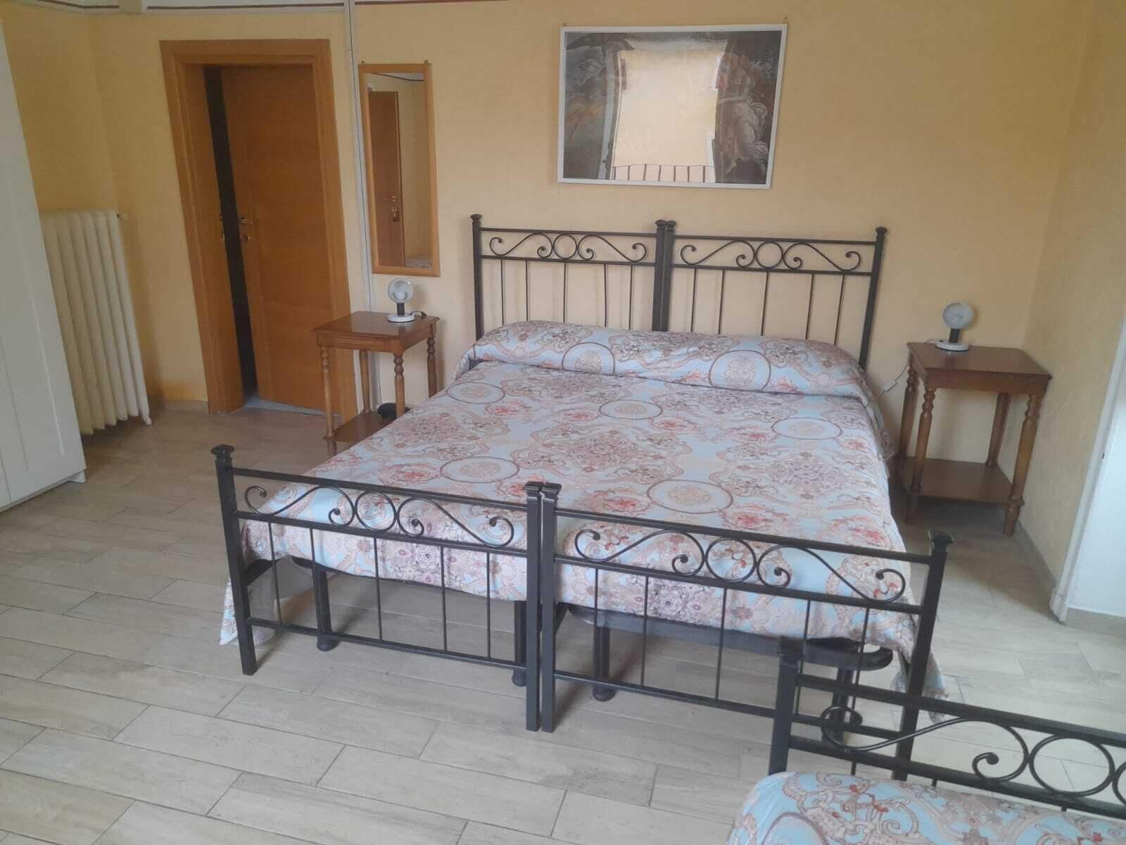 A bedroom with a bed, a wooden door, a mirror, and a small table.