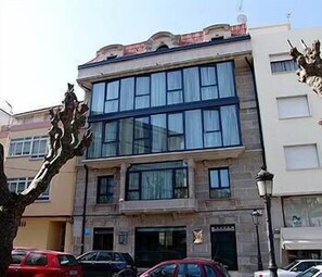 A multi-story building with large windows and a stone facade. - La Noyesa (O Grove)