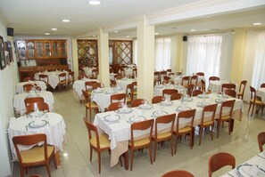 A dining area with multiple round tables, each set with white tablecloths, plates, and chairs. - La Noyesa (O Grove)