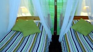 Una habitación con dos camas, cada una con almohada verde y ropa de cama a rayas.
