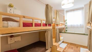 A bunk bed room with a window, a fan, and a small desk.