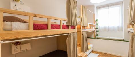A bunk bed room with a window, a fan, and a small desk.