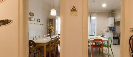 A dining area with wooden tables and chairs, a hanging light fixture, and a warning sign on the wall.