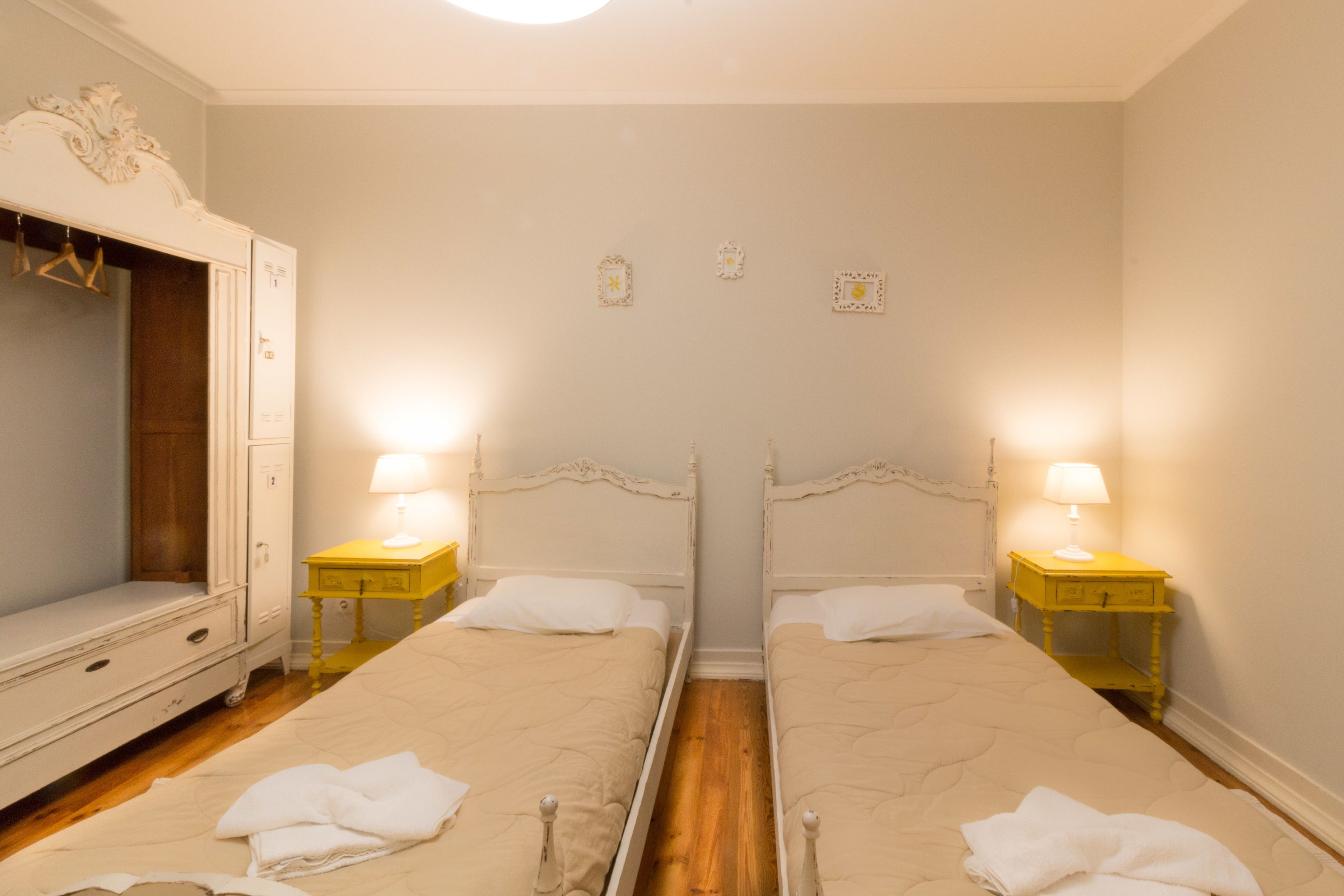 Habitación doble con dos camas, un armario y lámparas de noche.