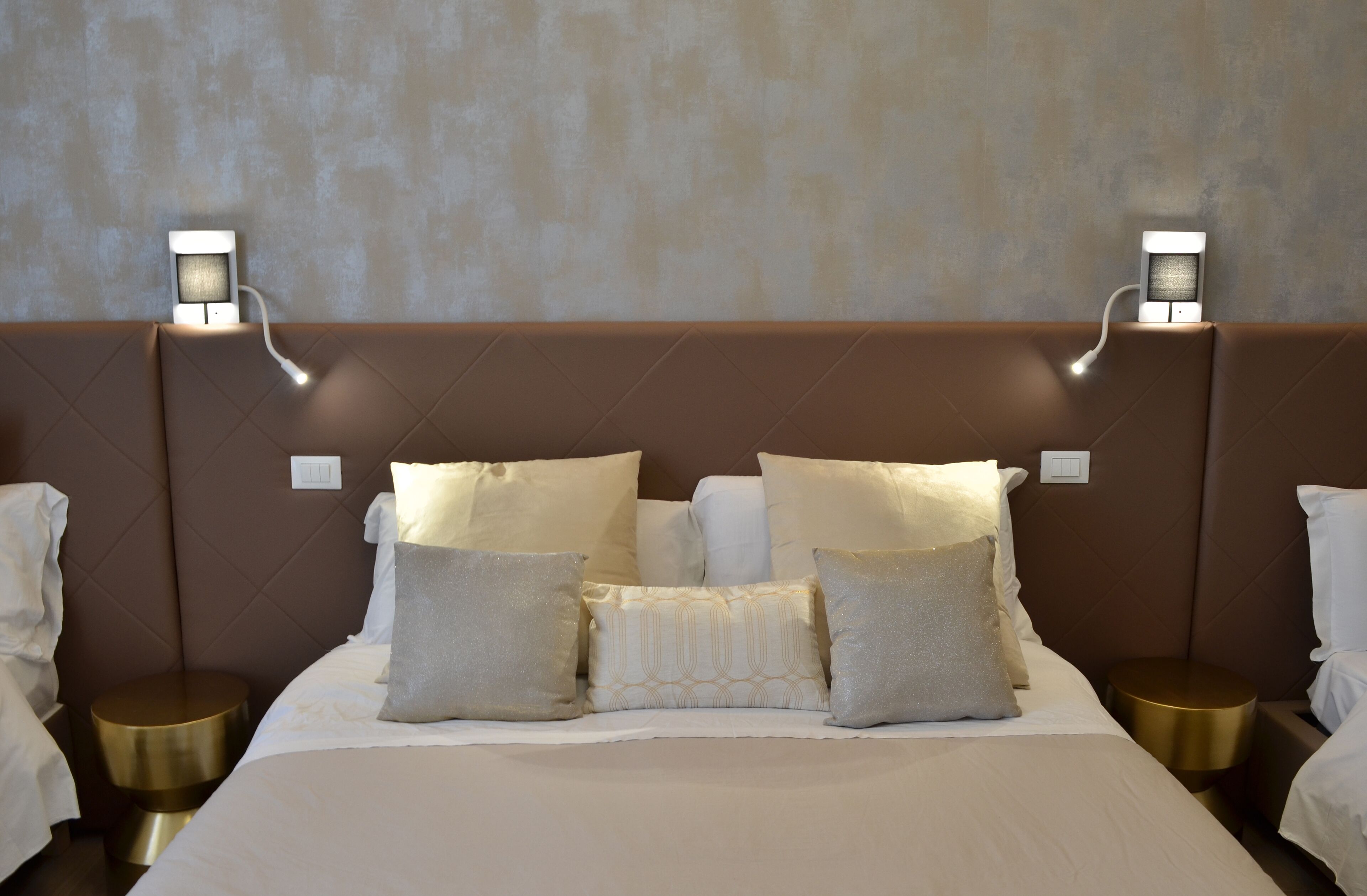 A neatly made bed with multiple pillows and two bedside tables with lamps.