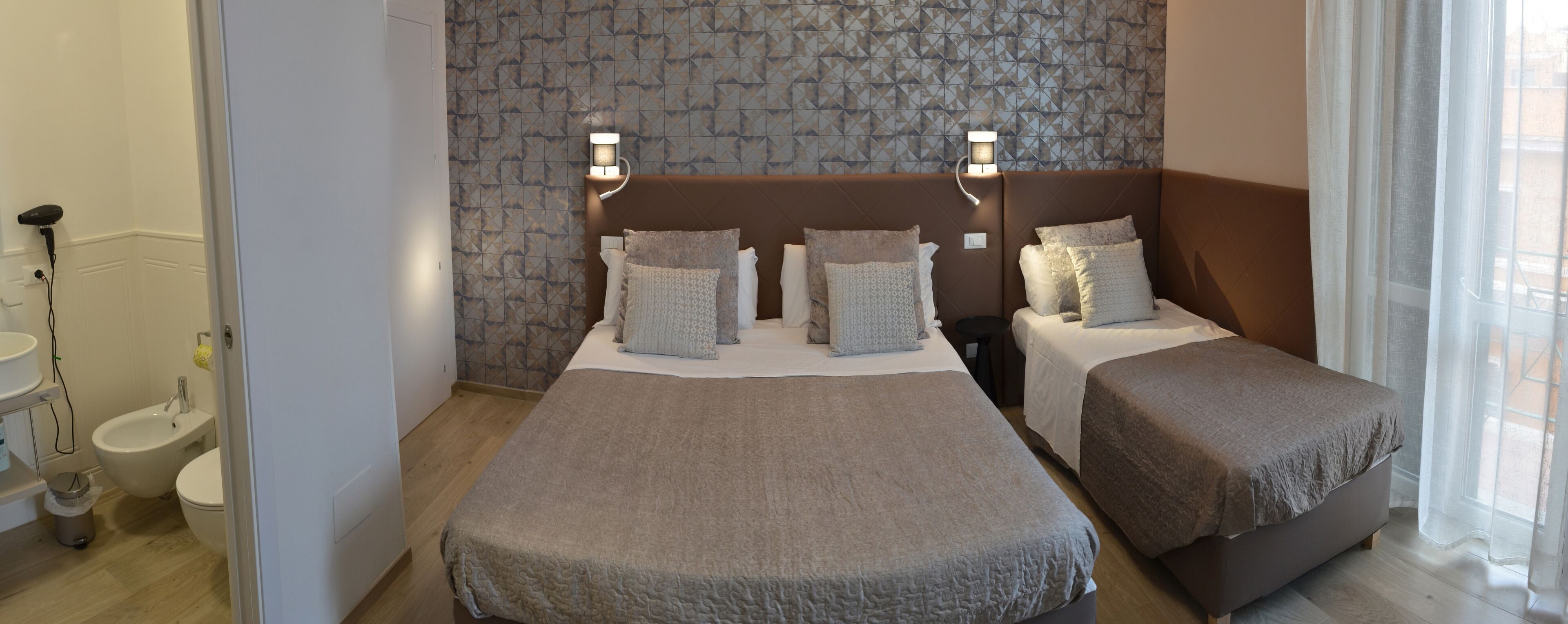 A hotel room with two single beds, a bidet, and a small bathroom.