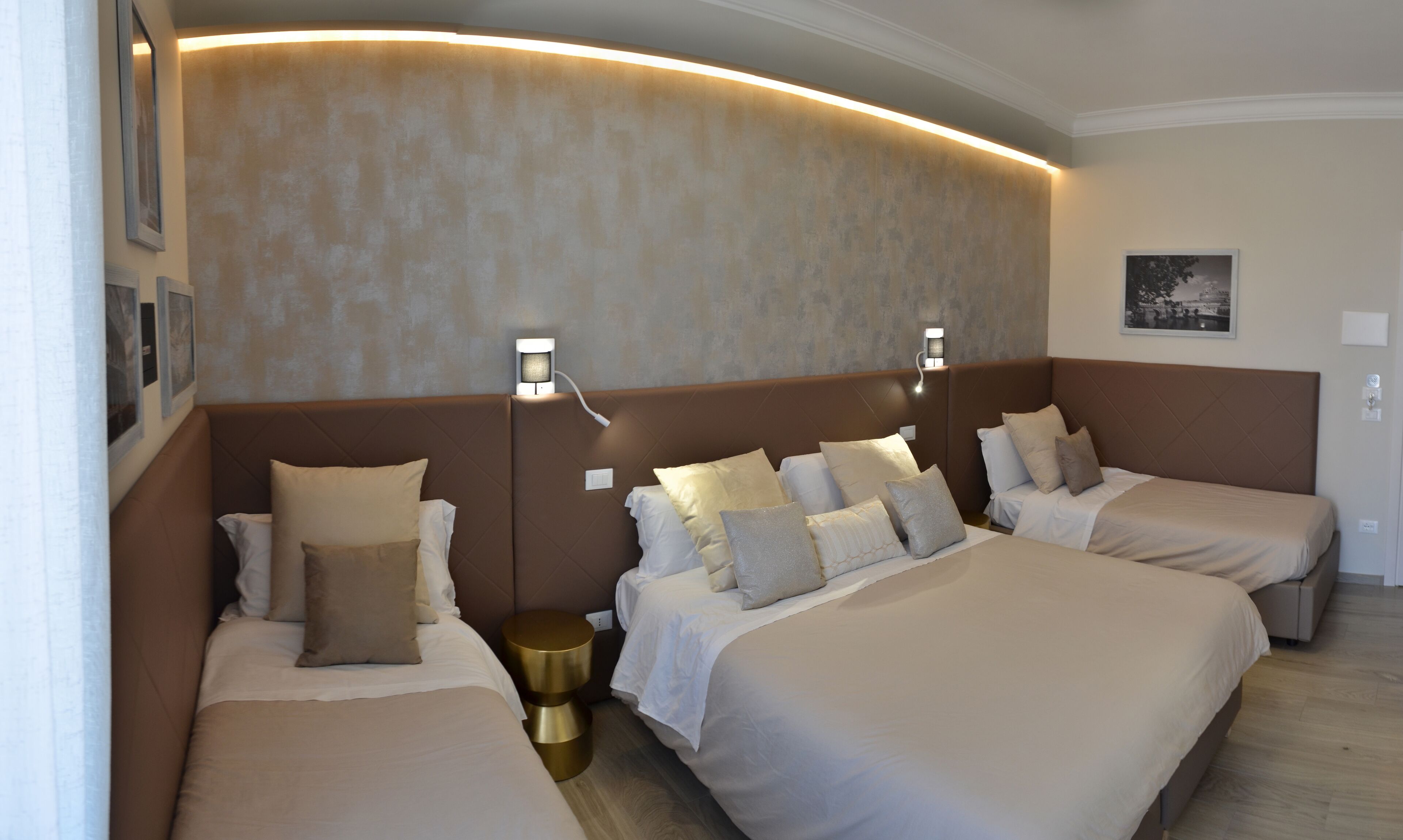 Ett hotellrum med två sängar, en böjd vägg och väggmonterad belysning.