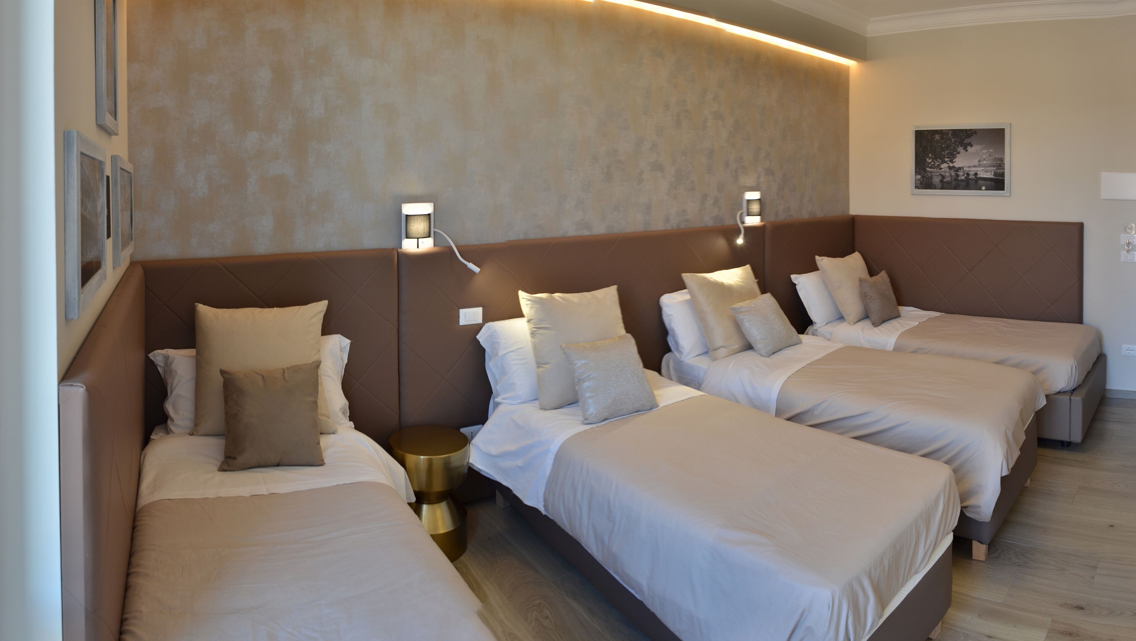 Habitación de hotel con tres camas individuales, cada una con una almohada y una mesita de noche.