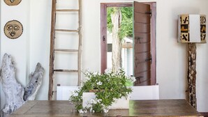 A rustic wooden table with a white cloth, two wooden chairs, a ladder, and a wooden door leading outside. - Ca' Maddalena (Villafranca di Verona)