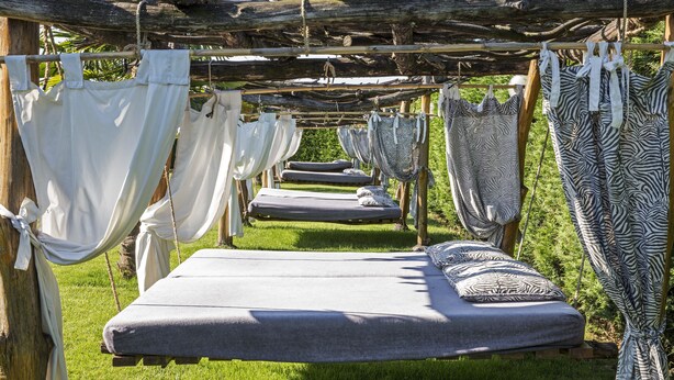 A row of hammocks suspended from a wooden structure, each with a mattress and pillows. - Ca' Maddalena (Villafranca di Verona)