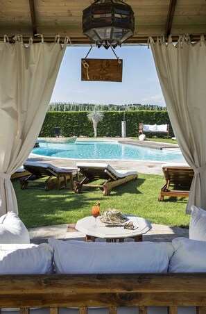 A poolside area with lounge chairs, a table with a drink, and a hanging sign.