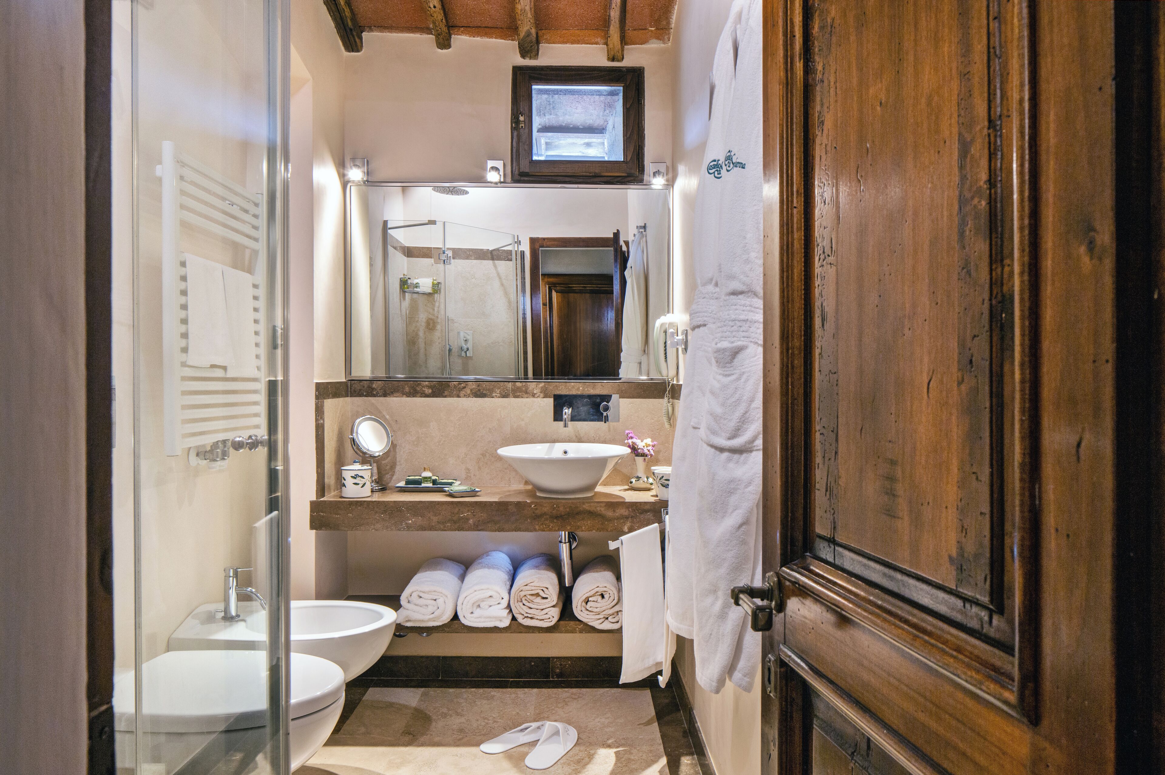 A bathroom with two sinks, a shower, and a wooden door.