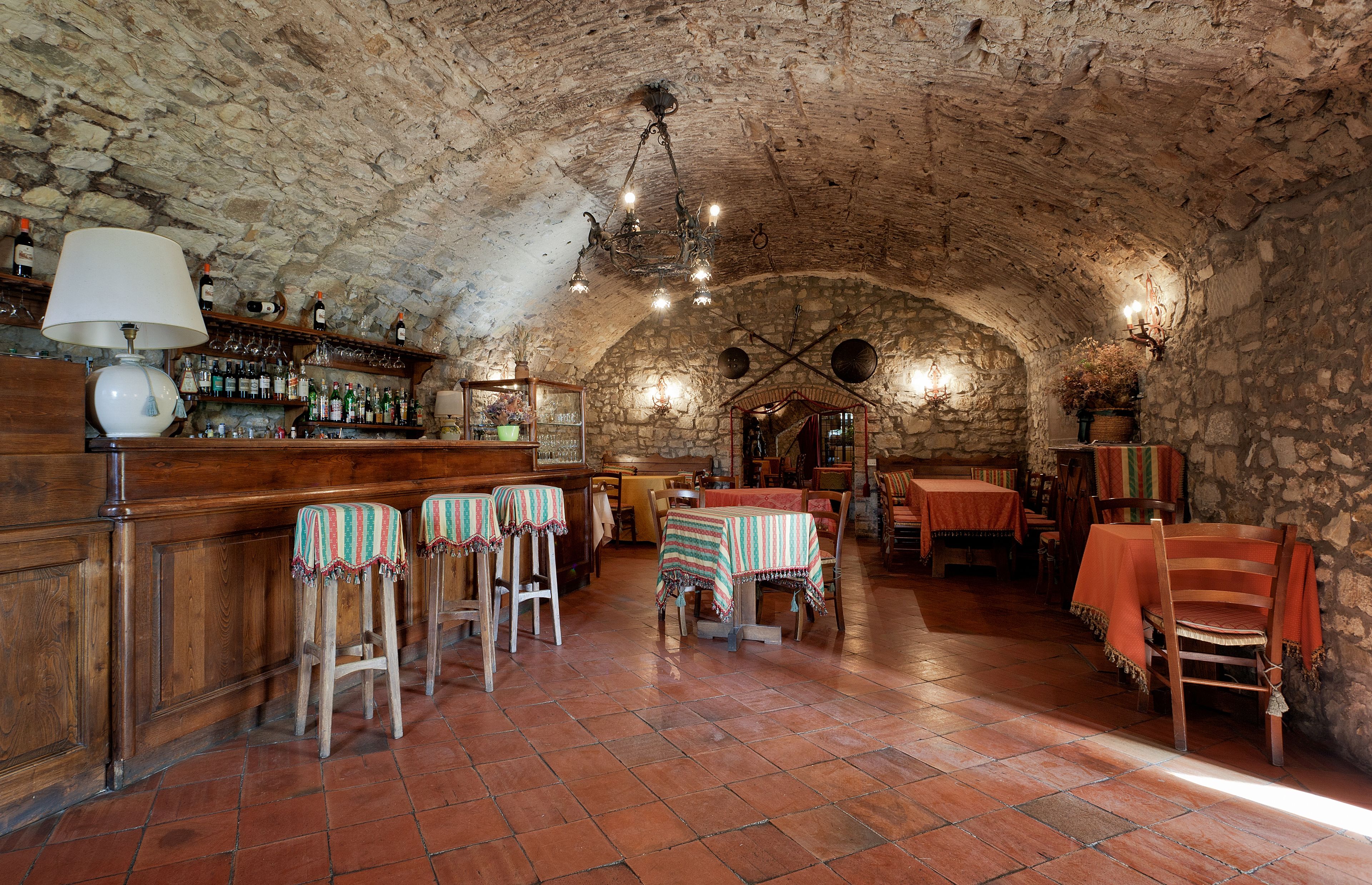 A rustic interior with stone walls, wooden furniture, and a bar area.