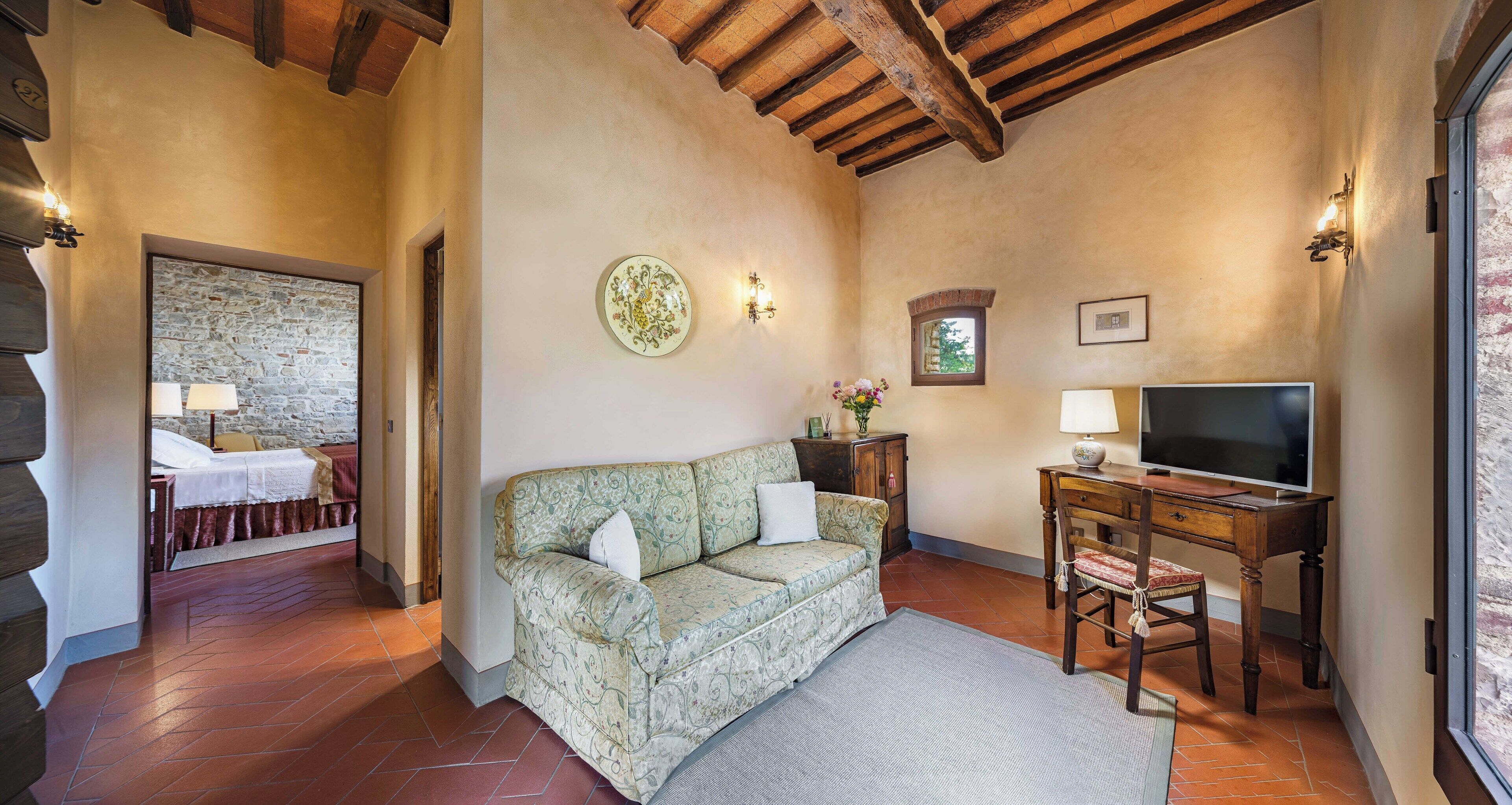 A cozy room with a sofa, a TV, a desk, and a stone wall.