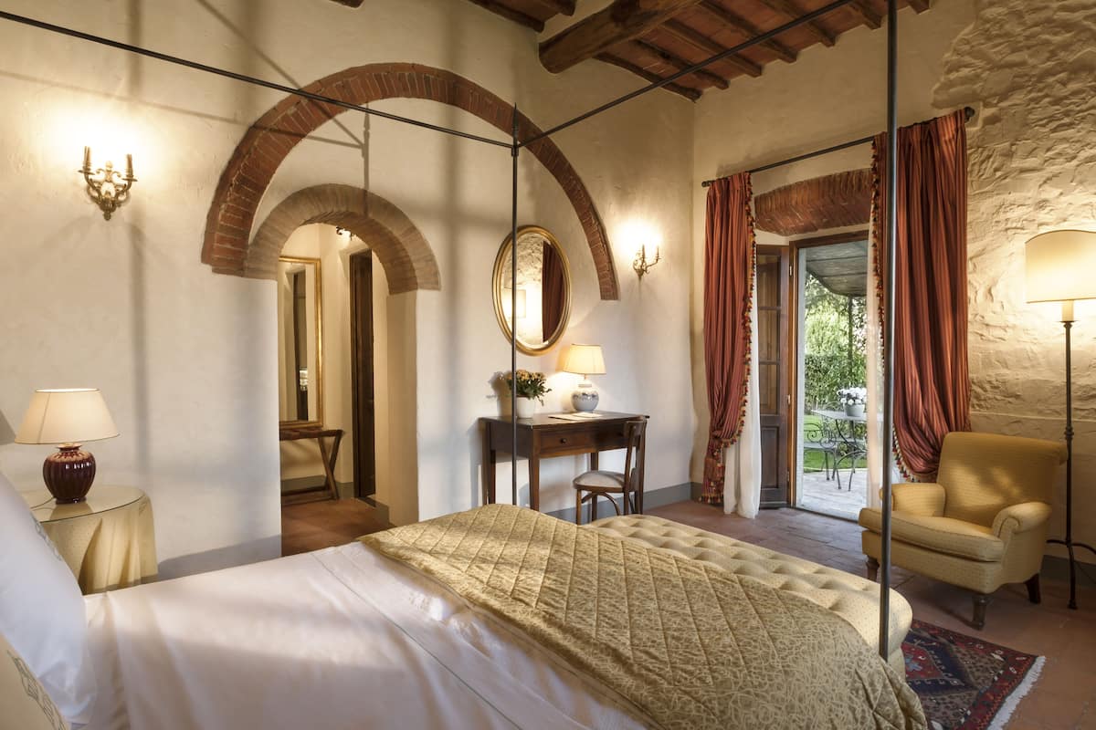 A bedroom with a bed, a desk, a chair, and a window with curtains.