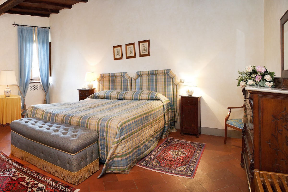A bedroom with a bed, a sofa, a small table, and a desk with a computer.